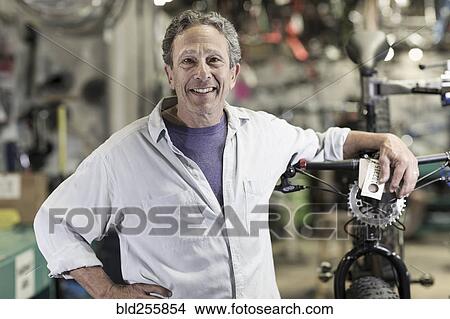 Portrait of smiling Caucasian man leaning on bicycle in shop View Large Photo Image Picture - Portrait of smiling Caucasian man leaning on bicycle in shop. Fotosearch