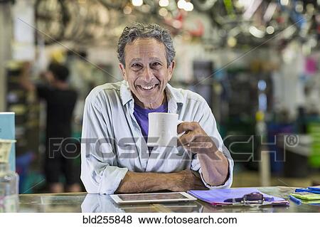 Portrait of smiling Caucasian man drinking coffee in bicycle shop View Large Photo Image Stock Photo - Portrait of smiling Caucasian man drinking coffee in bicycle shop. Fotosearch