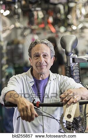Stock Photo - Portrait of smiling Caucasian man leaning on bicycle in shop. Fotosearch