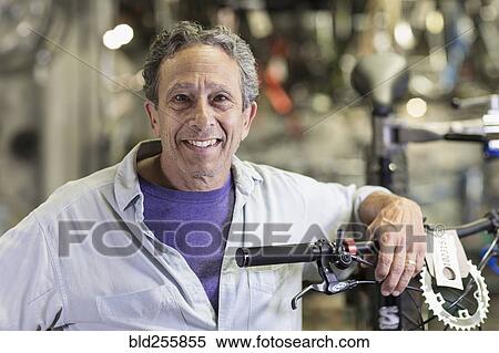Portrait of smiling Caucasian man leaning on bicycle in shop View Large Photo Image Stock Photography - Portrait of smiling Caucasian man leaning on bicycle in shop. Fotosearch