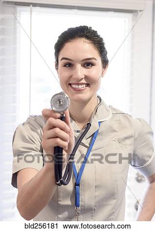 Stock Image - Portrait of smiling Caucasian nurse holding stethoscope. Fotosearch