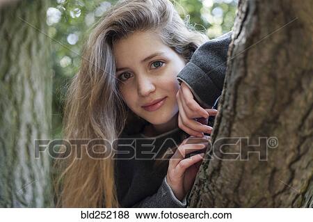 Stock Photo - Portrait of smiling Caucasian teenage girl leaning on tree. Fotosearch