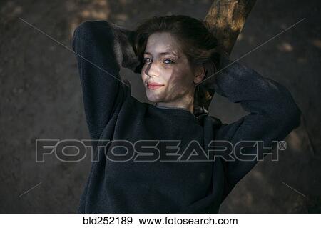 Stock Photo - Portrait of smiling Caucasian teenage girl leaning on tree. Fotosearch