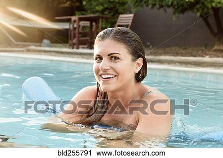 Stock Image - Portrait of smiling Caucasian woman in swimming pool. Fotosearch