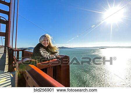 Stock Image - Portrait of smiling Caucasian woman on bridge. Fotosearch