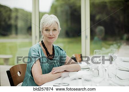 Picture - Portrait of smiling Caucasian woman sitting at table in restaurant. Fotosearch