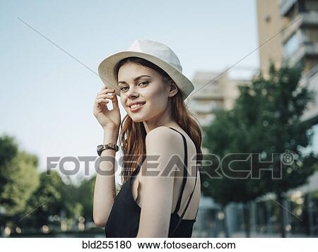 Stock Image - Portrait of smiling Caucasian woman holding hat. Fotosearch