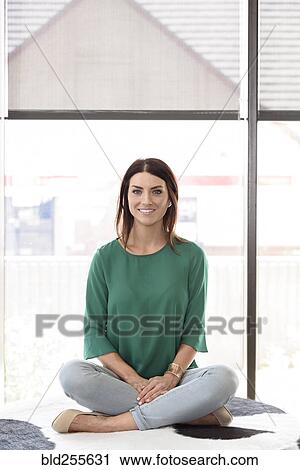 Stock Image - Portrait of smiling Caucasian woman sitting on bench. Fotosearch