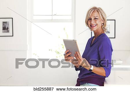 Portrait of smiling Caucasian woman holding digital tablet View Large Photo Image Stock Photo - Portrait of smiling Caucasian woman holding digital tablet. Fotosearch