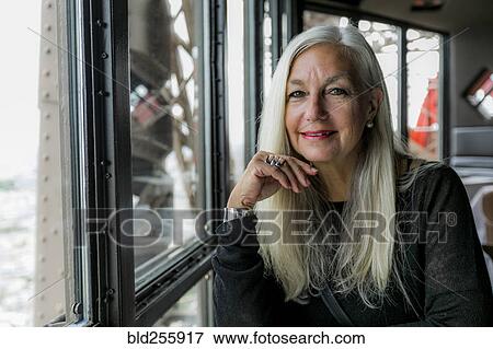 Stock Photo - Portrait of smiling Caucasian woman near window. Fotosearch