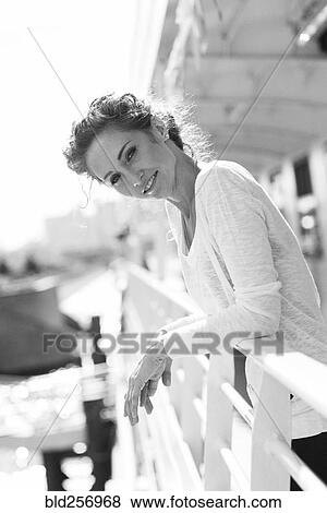 Stock Photo - Portrait of smiling Caucasian woman leaning on railing. Fotosearch