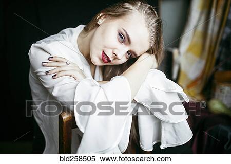 Stock Photography - Portrait of smiling Caucasian woman leaning on chair. Fotosearch