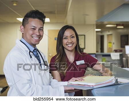 Portrait of smiling doctor and nurse with binder in hospital View Large Photo Image Picture - Portrait of smiling doctor and nurse with binder in hospital. Fotosearch
