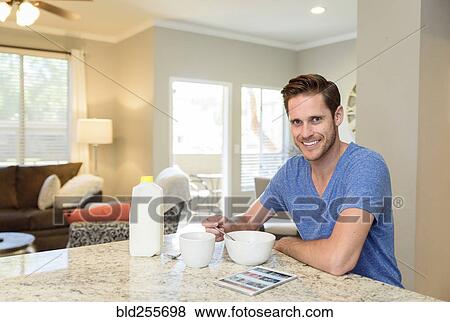 Portrait of smiling man eating bowl of cereal in morning View Large Photo Image Stock Photo - Portrait of smiling man eating bowl of cereal in morning. Fotosearch