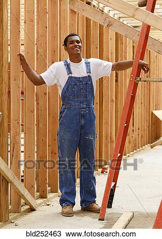 Portrait of smiling mixed race man leaning on ladder at construction site View Large Photo Image Stock Image - Portrait of smiling mixed race man leaning on ladder at construction site. Fotosearch