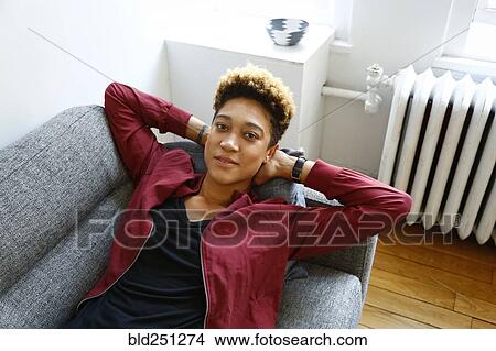 Picture - Portrait of smiling mixed race woman relaxing on sofa. Fotosearch