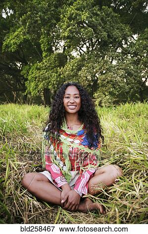 Portrait of smiling mixed race woman sitting in grass View Large Photo Image Stock Photo - Portrait of smiling mixed race woman sitting in grass. Fotosearch