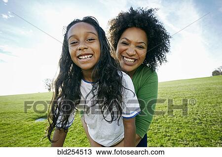 Stock Image - Portrait of smiling mixed raced mother and daughter. Fotosearch