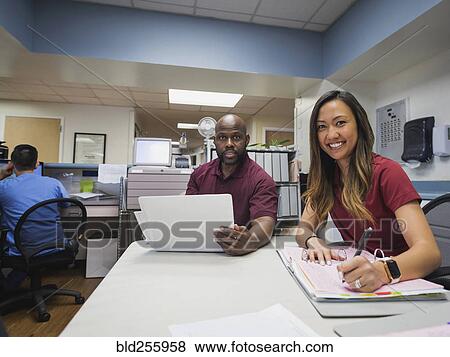 Stock Photo - Portrait of smiling nurses with binders and hospital. Fotosearch