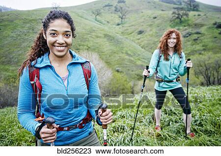 Stock Image - Portrait of smiling women hiking with walking sticks. Fotosearch