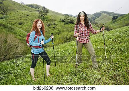 Stock Photograph - Portrait of smiling women hiking with walking sticks. Fotosearch