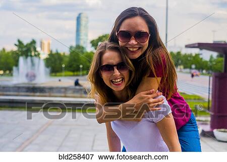 Portrait of smiling women hugging View Large Photo Image Stock Photo - Portrait of smiling women hugging. Fotosearch