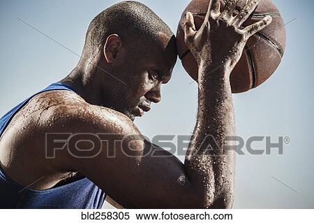 Stock Photography - Portrait of sweating Black man touching forehead with basketball. Fotosearch