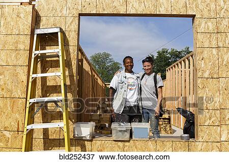 Portrait of volunteers behind window frame at construction site View Large Photo Image Stock Photo - Portrait of volunteers behind window frame at construction site. Fotosearch