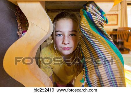 Stock Photo - Portraits of serious Caucasian girl under table. Fotosearch