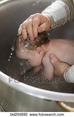 Stock Image - Priest baptizing baby girl with water. Fotosearch