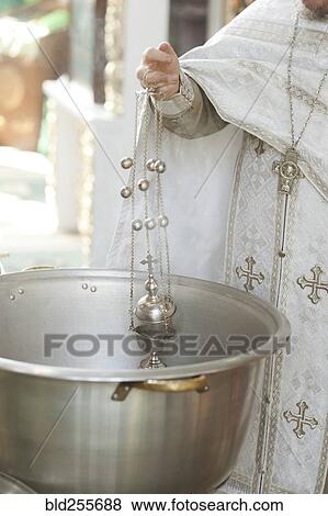 Stock Photo - Priest holding chalice in bowl. Fotosearch