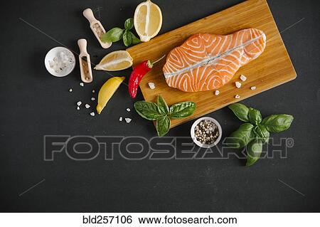 Stock Photograph - Raw salmon on cutting board with ingredients. Fotosearch