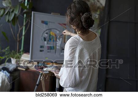 Stock Photo - Rear view of Caucasian woman painting on easel. Fotosearch