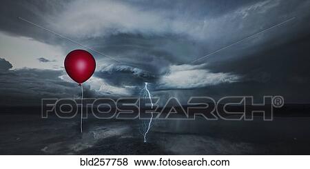 Stock Photo - Red balloon floating in stormy sky. Fotosearch