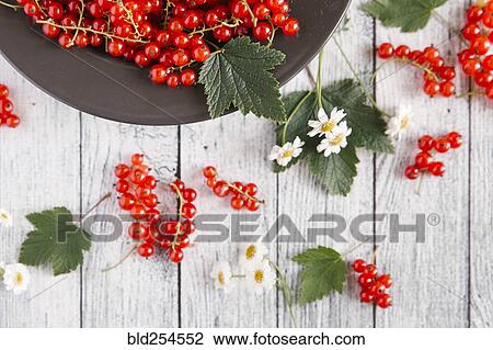 Stock Image - Red berries and leaves on table with flowers. Fotosearch
