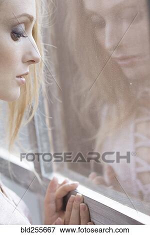Stock Photo - Reflection of Caucasian woman leaning on window. Fotosearch