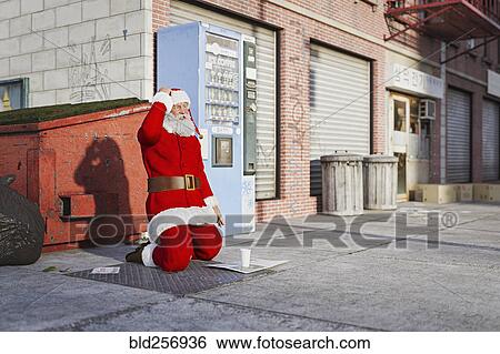 Stock Photograph - Santa kneeling on sidewalk begging. Fotosearch