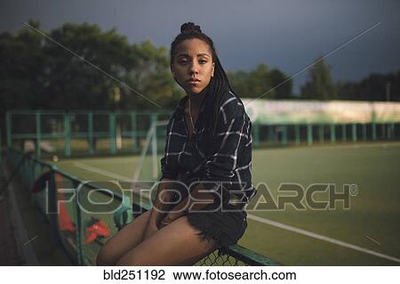 Serious African American woman sitting on fence at sports field View Large Photo Image Stock Image - Serious African American woman sitting on fence at sports field. Fotosearch