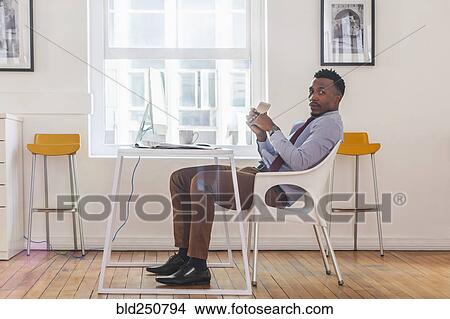 Serious Black businessman posing at computer desk View Large Photo Image Picture - Serious Black businessman posing at computer desk. Fotosearch