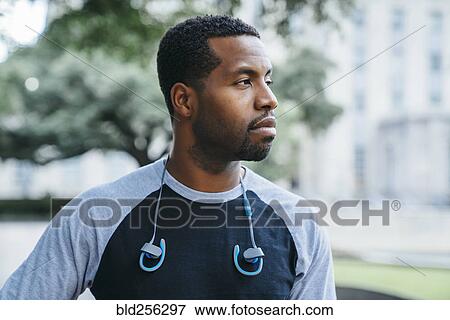 Serious Black man with earbuds looking away View Large Photo Image Stock Photo - Serious Black man with earbuds looking away. Fotosearch