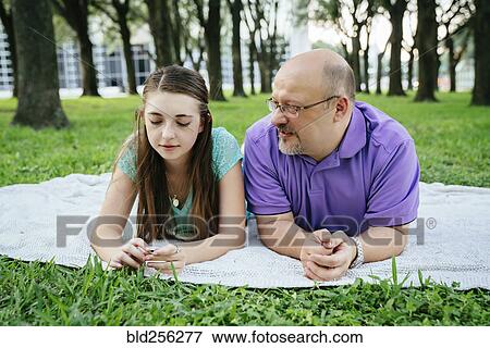 Stock Photo - Serious Caucasian father and daughter talking on blanket in park. Fotosearch