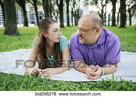 Stock Photo - Serious Caucasian father and daughter talking on blanket in park. Fotosearch