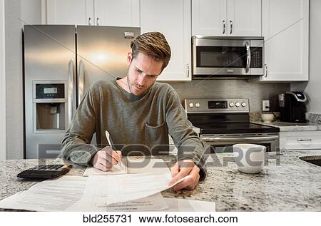 Serious Caucasian man writing notes and reading paperwork View Large Photo Image Stock Image - Serious Caucasian man writing notes and reading paperwork. Fotosearch