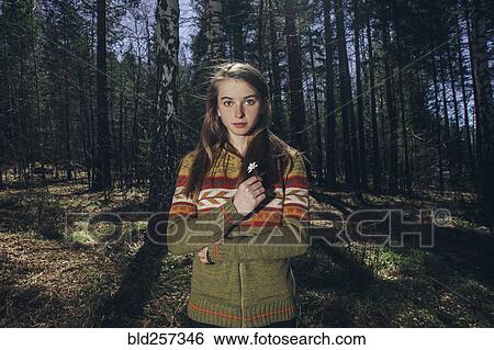 Serious Caucasian woman holding flower in forest View Large Photo Image Stock Photograph - Serious Caucasian woman holding flower in forest. Fotosearch