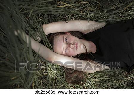 Serious Caucasian woman laying in tall grass View Large Photo Image Stock Photography - Serious Caucasian woman laying in tall grass. Fotosearch