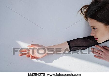 Stock Photo - Serious Caucasian woman reaching for light. Fotosearch
