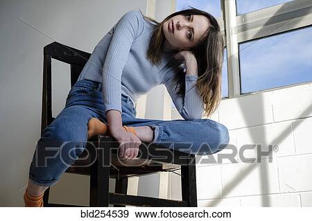 Serious Caucasian woman sitting in chair near window View Large Photo Image Stock Photo - Serious Caucasian woman sitting in chair near window. Fotosearch