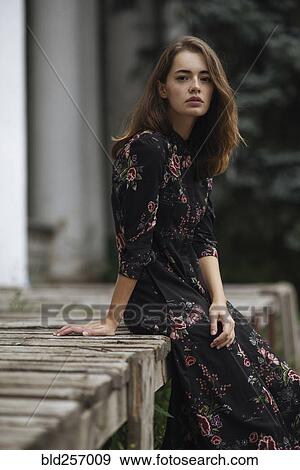 Stock Photo - Serious Caucasian woman sitting on wooden porch. Fotosearch
