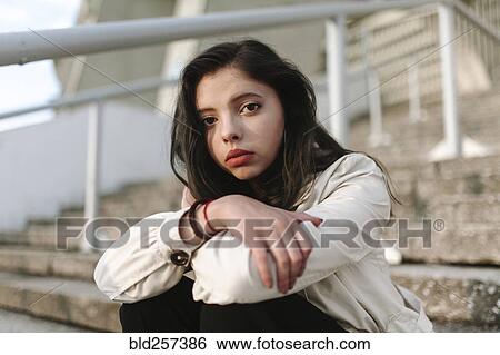 Stock Photograph - Serious Caucasian woman sitting on staircase. Fotosearch