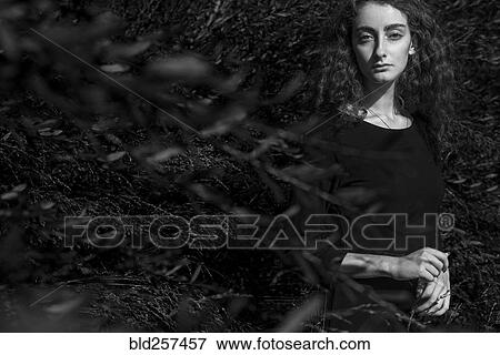 Stock Photo - Serious Caucasian woman standing behind branches. Fotosearch